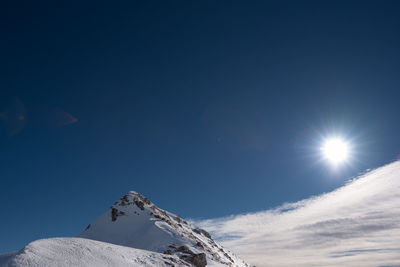 Low angle view of snowcapped mountain against blue sky