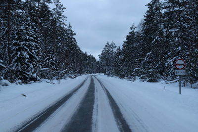 Road amidst snow covered trees against sky