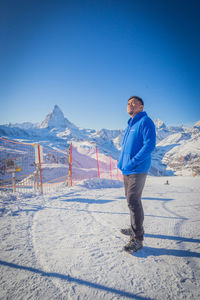 Side view of man standing on snow covered mountain with background of matterhorn peak