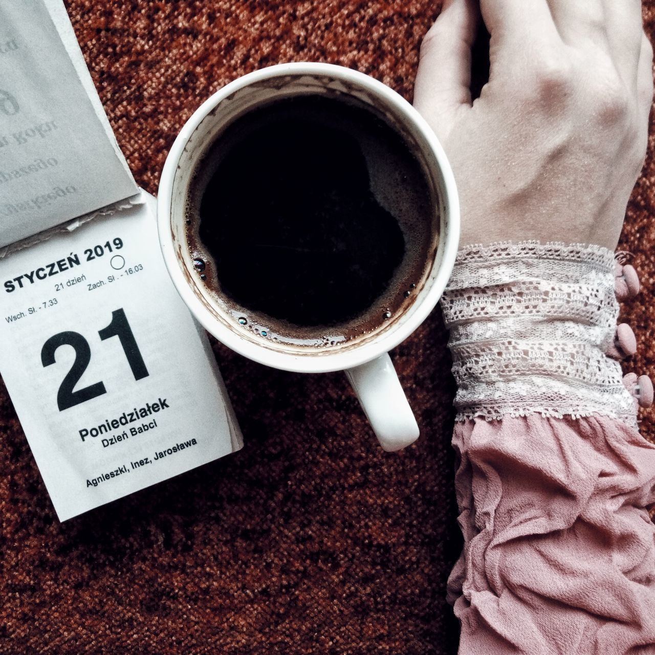 drink, indoors, black coffee, coffee, coffee - drink, cup, coffee cup, high angle view, text, refreshment, mug, directly above, food and drink, book, one person, publication, still life, table, human body part, black tea