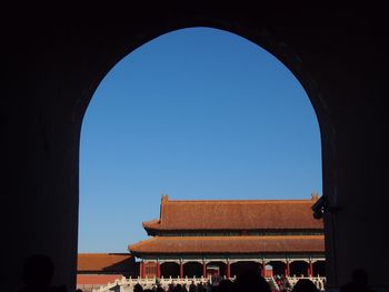 Building seen through arch against clear blue sky