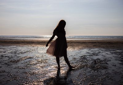 Woman standing at beach against sky