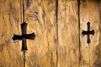 Close-up of cross on wood against wall