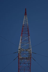 Low angle view of electricity pylon against clear blue sky