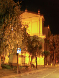 Illuminated built structure against trees at night