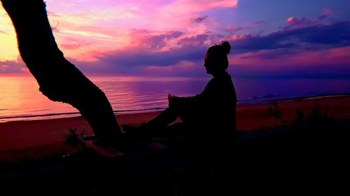 Silhouette woman by sea against sky during sunset