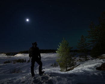 Full length of man standing on snow covered field against sky at night