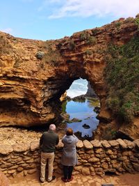 Rear view of couple standing by rock formation