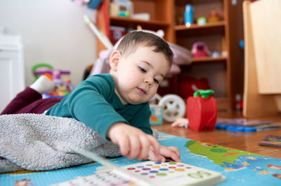 Young toddler boy looking at books and playing in his room