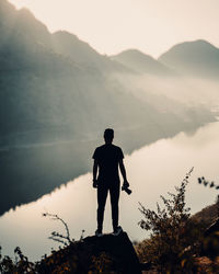 Rear view of man standing on cliff against mountain