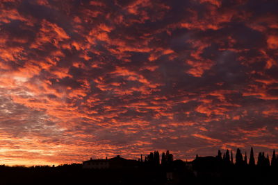 Silhouette buildings against dramatic sky during sunset