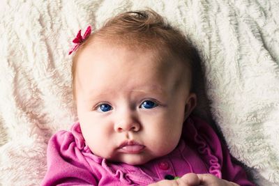 Close-up portrait of baby relaxing on bed