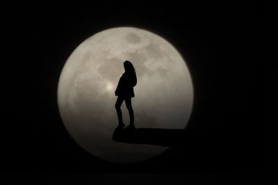 Silhouette woman standing on wall against moon at night