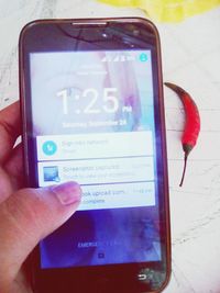 Cropped image of hand holding smart phone