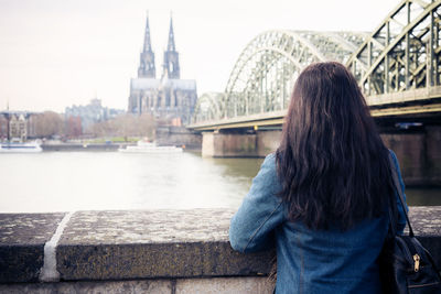 Rear view of woman standing on bridge over river