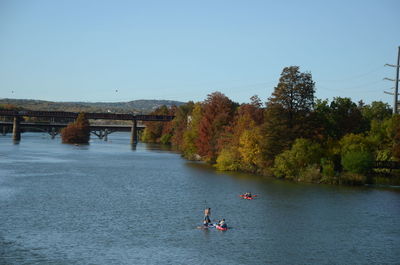 People on river against clear sky during autumn