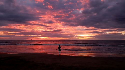 Silhouette person on beach against sky during sunset