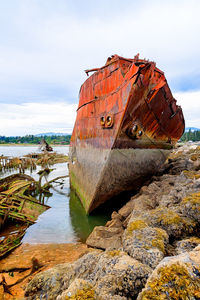 Abandoned boat on beach against sky