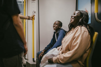 Happy male and female friends talking while travelling in subway train