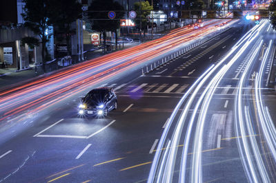 Car amidst light trails on road at night