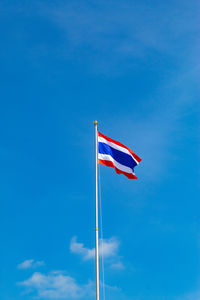 Low angle view of flag against blue sky