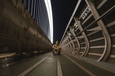 Portrait of woman sitting on footbridge at night