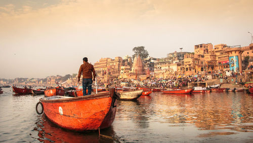 Man with boat in sea against sky