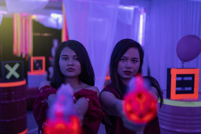 Portrait of female friends holding squirt guns in nightclub
