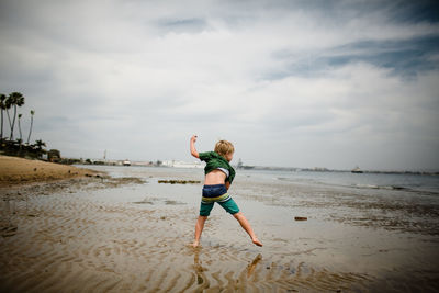 Full length of boy on beach against sky