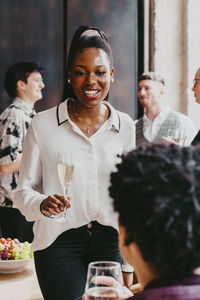 Smiling businesswoman holding drink glass during event at convention center