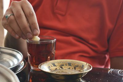 Close-up of man dipping cookie in tea on table