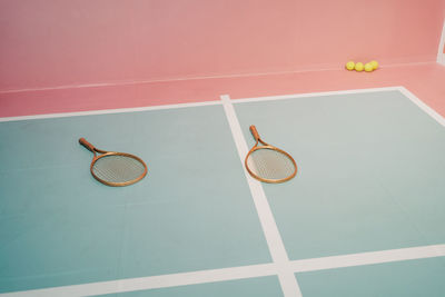 Creative design of tennis rackets against small balls on sports ground with marking lines