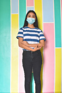 Portrait of young woman standing against wall