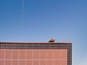 Low angle view of a bulding with solar panels against clear blue sky