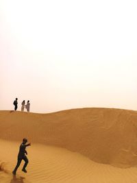 Men at desert against clear sky