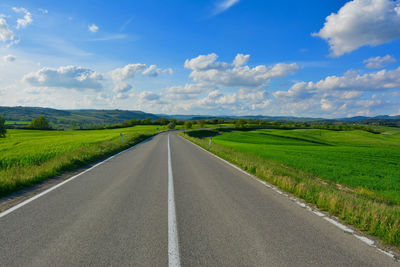 Road amidst field against sky