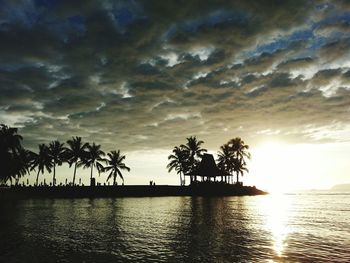 Silhouette palm trees on beach against sky during sunset