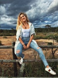 Full length portrait of happy woman sitting on field