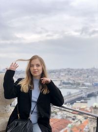 Portrait of beautiful young woman standing against sky