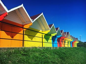 Multi colored houses on field against clear blue sky