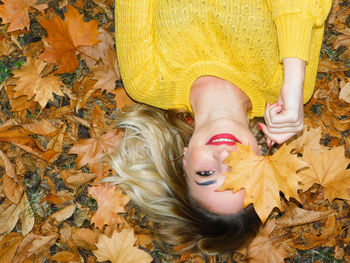 High angle view of woman lying on yellow autumn leaves