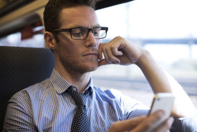 Businessman using smart phone while traveling in train