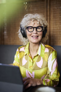 Portrait of smiling senior woman with headphones using tablet