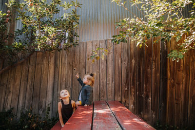 Two happy girls playing together at a picnic table under a tree