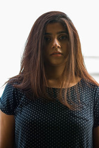 Portrait of beautiful young woman standing against wall