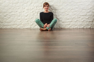 Portrait of woman sitting on wooden floor at home