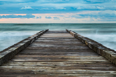 Surface level of wooden pier over sea against sky