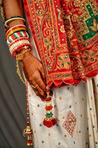 Midsection of bride in traditional clothing over gray background