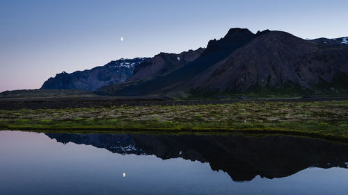 Scenic view of lake and mountains against sky at night