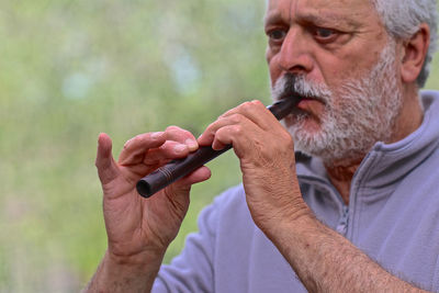 Portrait of man holding cigarette outdoors